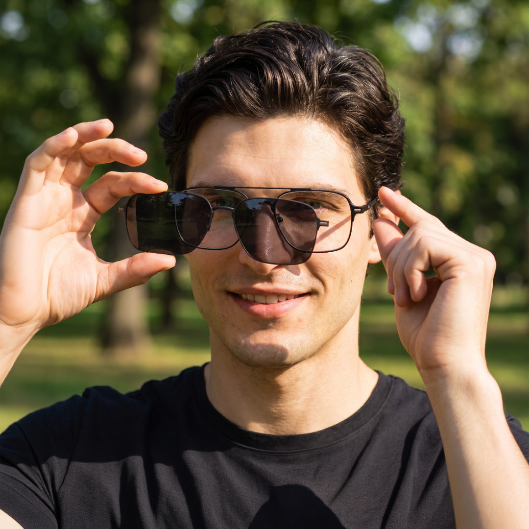 Homem ao ar livre encaixando uma lente magnética solar na armação do kit de viagem